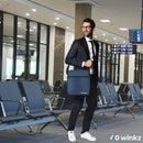 Man in suit carrying navy blue travel bag with shoulder strap at airport gate seating area