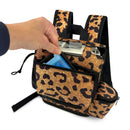 Hand placing item in leopard print backpack for portable oxygen concentrator, front view