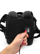 Hand plugging cable into black mesh portable oxygen concentrator backpack
