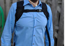 Man wearing black Inogen One G3 backpack with chest strap over blue shirt outdoors