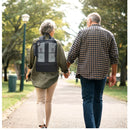 Woman wearing an oxygen concentrator backpack walking in park with man, portable oxygen bag